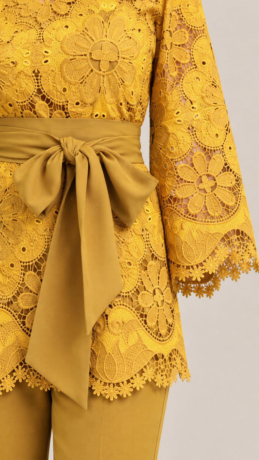 Close-up of floral lace fabric detail, 3/4 sleeves, and tie belt in mustard yellow