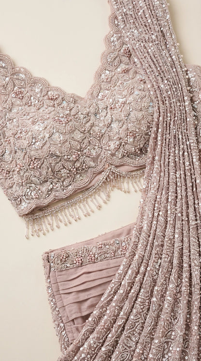 Close-up detail of beaded floral embroidery, scalloped hem, and sequined pleats