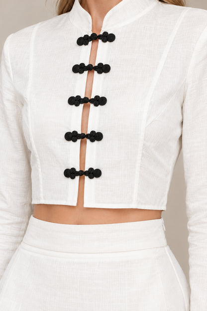 Close-up detail of white mandarin collar crop top with black frog knot buttons