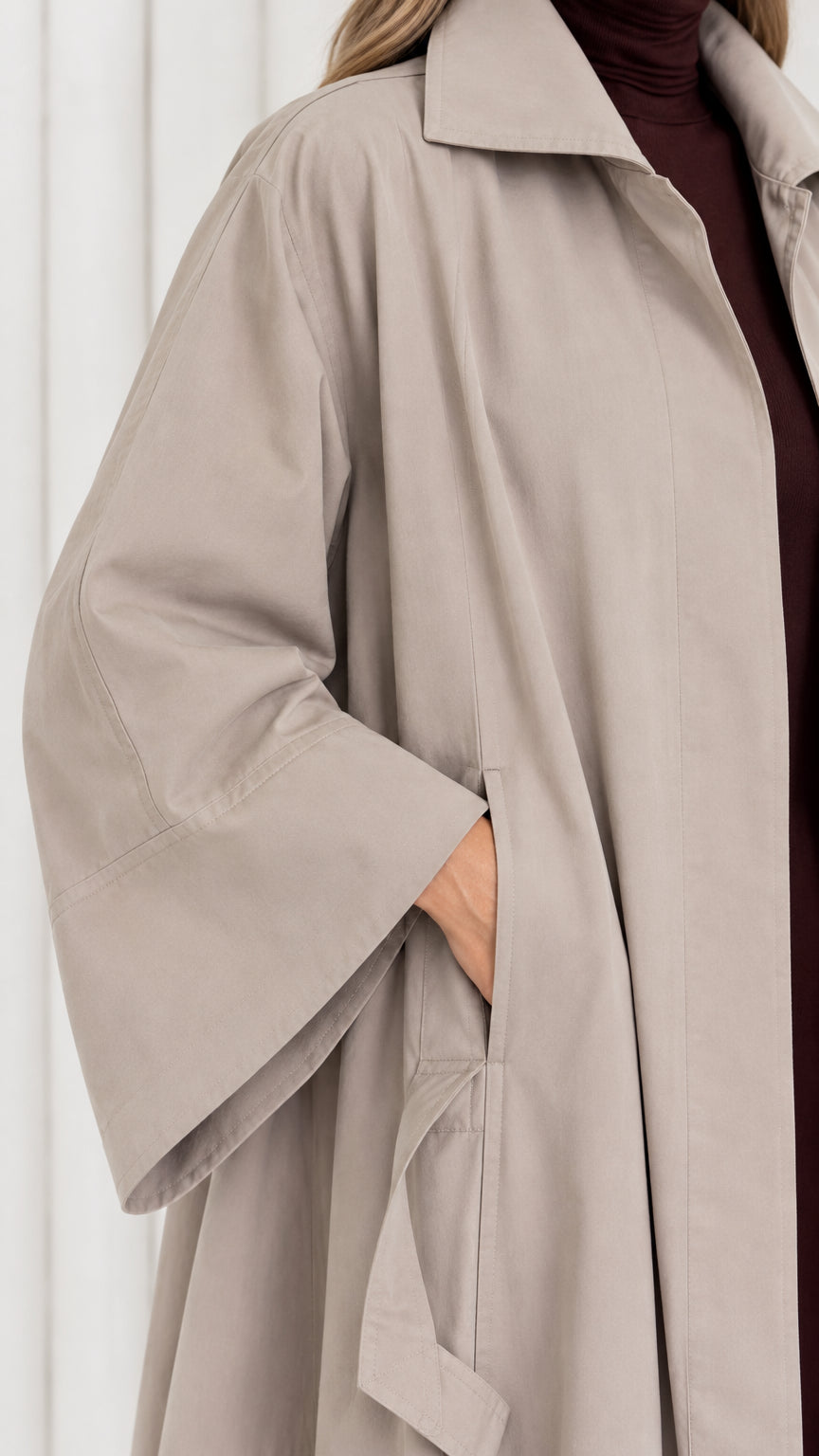Close-up detail of taupe trench coat spread collar, sleeve, and pocket