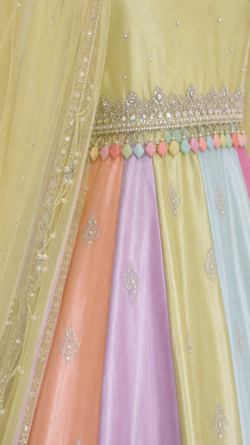 Close-up detail of embroidered waistband with colorful bead fringe and panel fabric