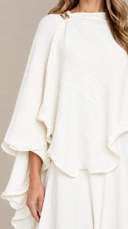 Close-up detail of textured fabric and shoulder hardware on white capelet top