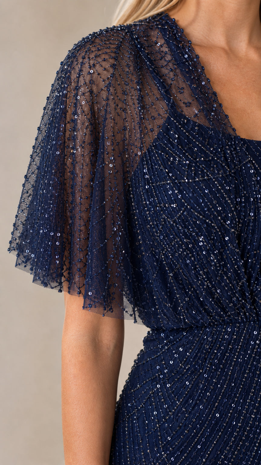 Close-up detail of sheer beaded flutter sleeve on navy formal dress