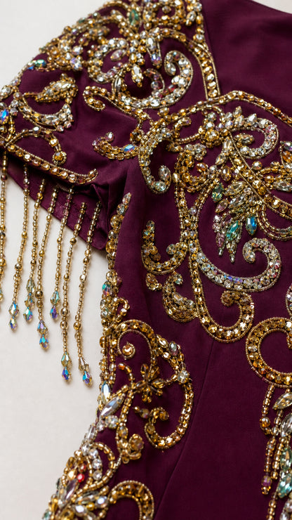 Close-up detail of intricate crystal beadwork, gold embroidery, and beaded tassels on cap sleeve