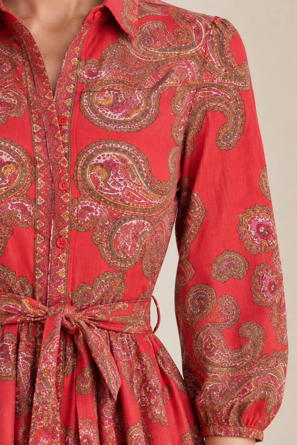 Close-up detail of red paisley fabric, collar, buttons, and waist tie
