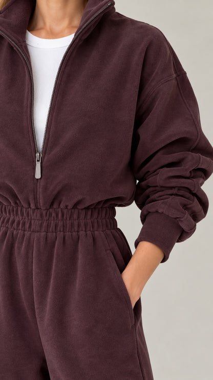 Close-up detail of half-zip neckline and smocked waist on chocolate fleece jumpsuit