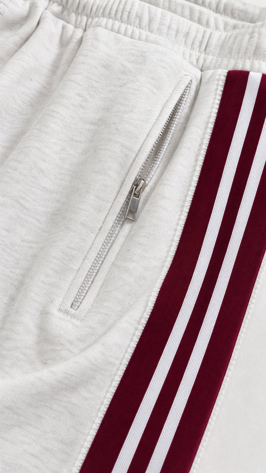 Close-up detail of white track pant zipper pocket and striped side trim