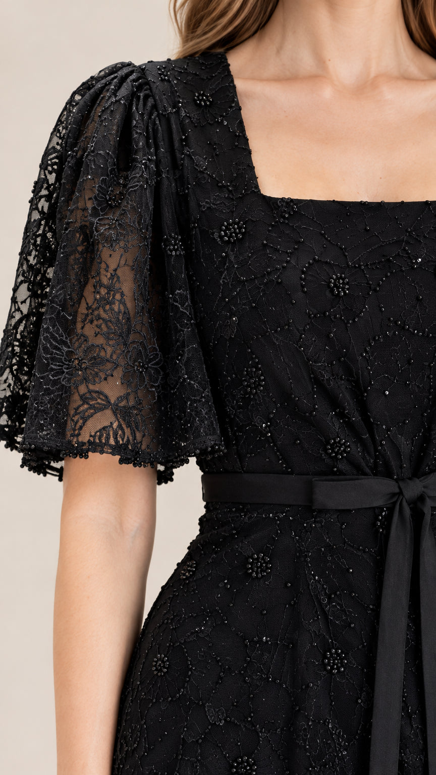 Close-up of black beaded floral lace texture and flutter sleeve detail