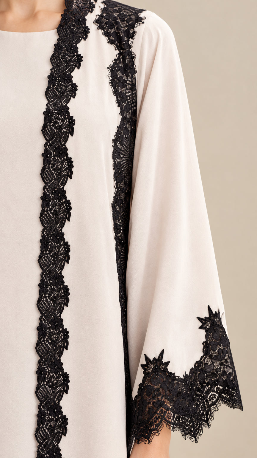 Close-up detail of delicate black floral lace trim on cream sleeve and bodice