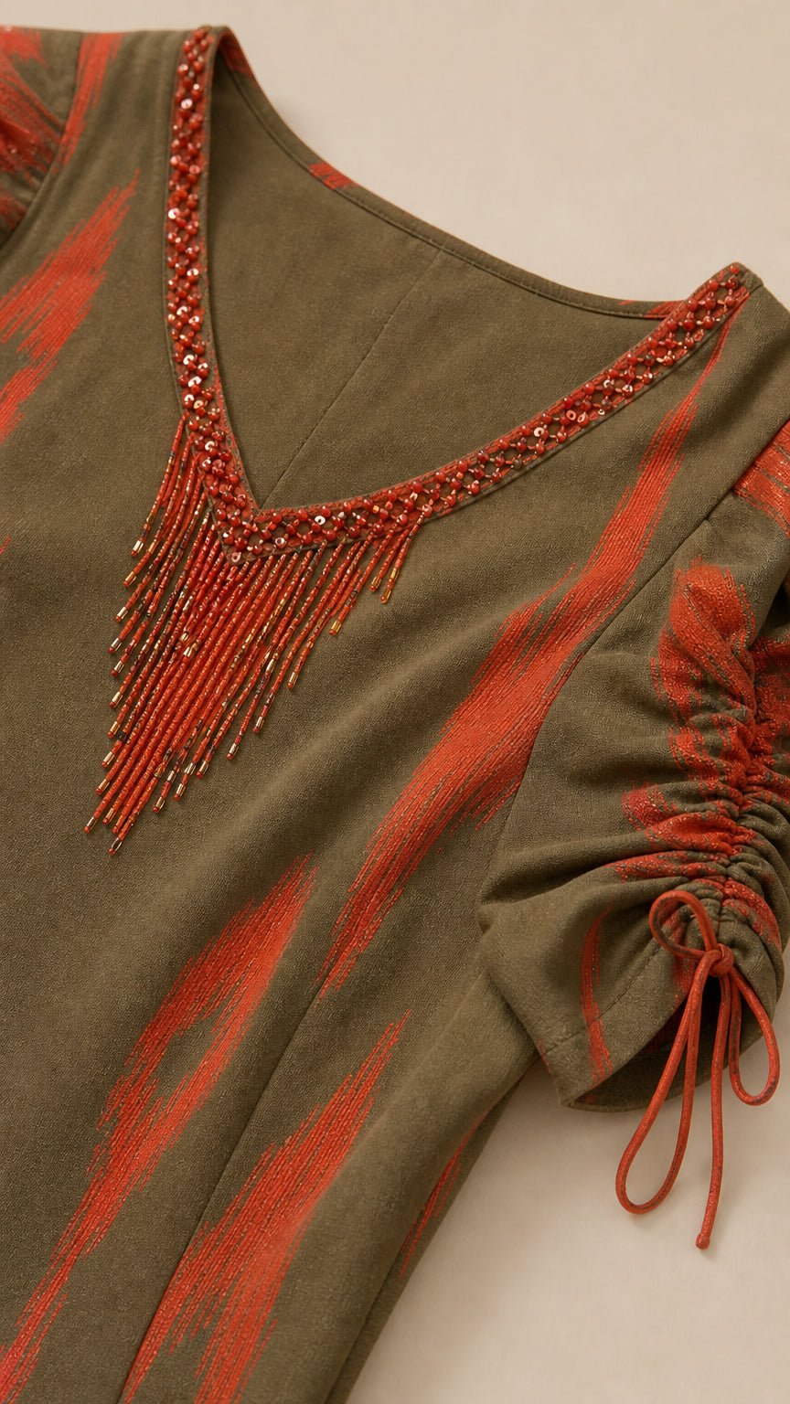 Close-up of beaded V-neck fringe trim and ruched sleeve detail on olive green dress