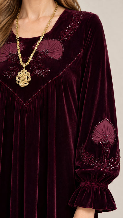 Close-up of intricate embroidery and beaded details on neckline and sleeve cuff of burgundy velvet dress