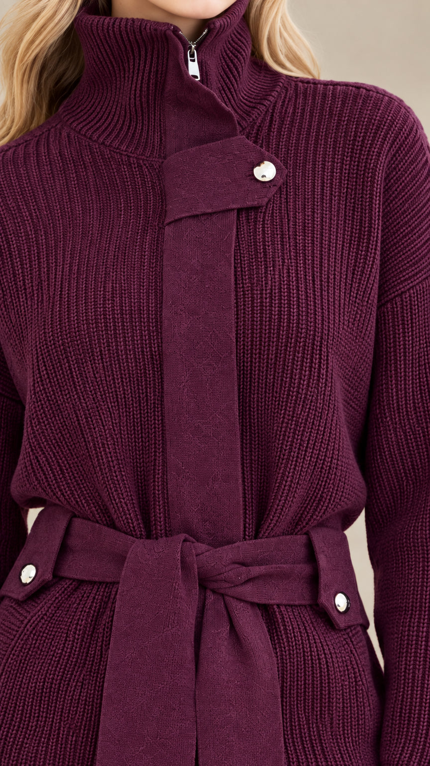 Close-up detail of high neck zipper, flap hardware, belt loops, and ribbed knit texture in plum