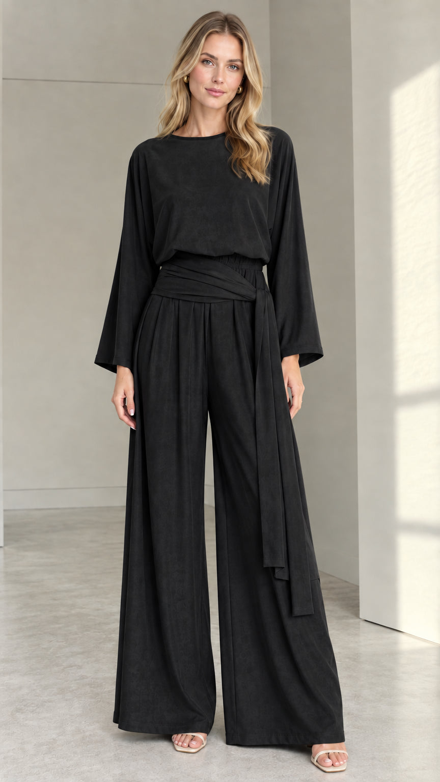 Front full view of woman wearing black long-sleeve wide-leg jumpsuit