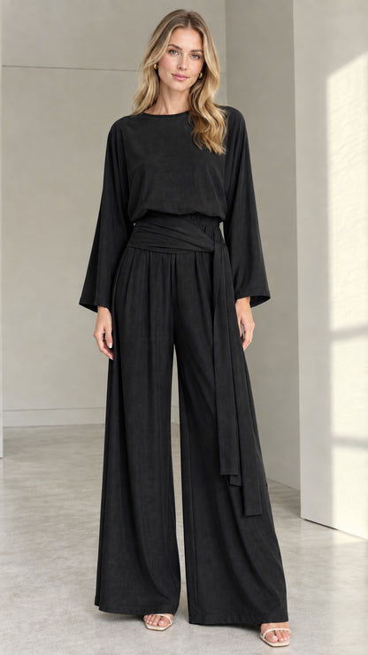 Front full view of woman wearing black long-sleeve wide-leg jumpsuit