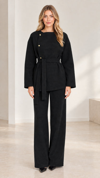 Full-length studio shot of model wearing classic black asymmetrical belted pant set