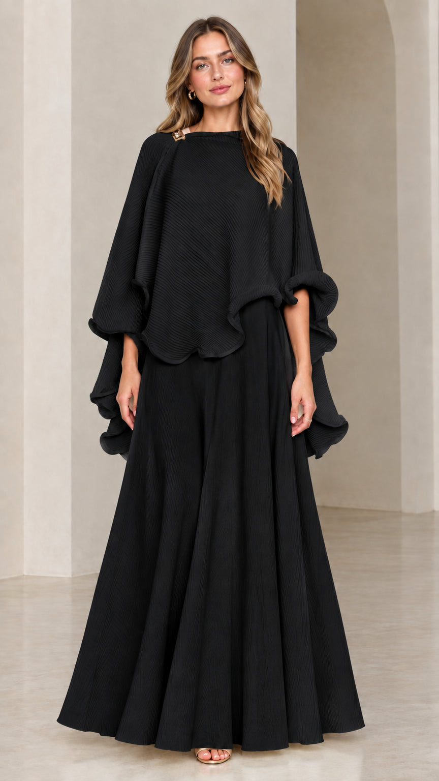 Model wearing black asymmetrical capelet top and maxi skirt set
