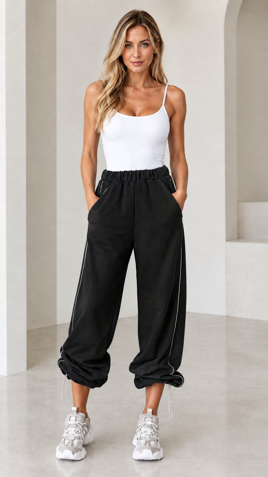Model wearing black relaxed fit joggers with white side piping