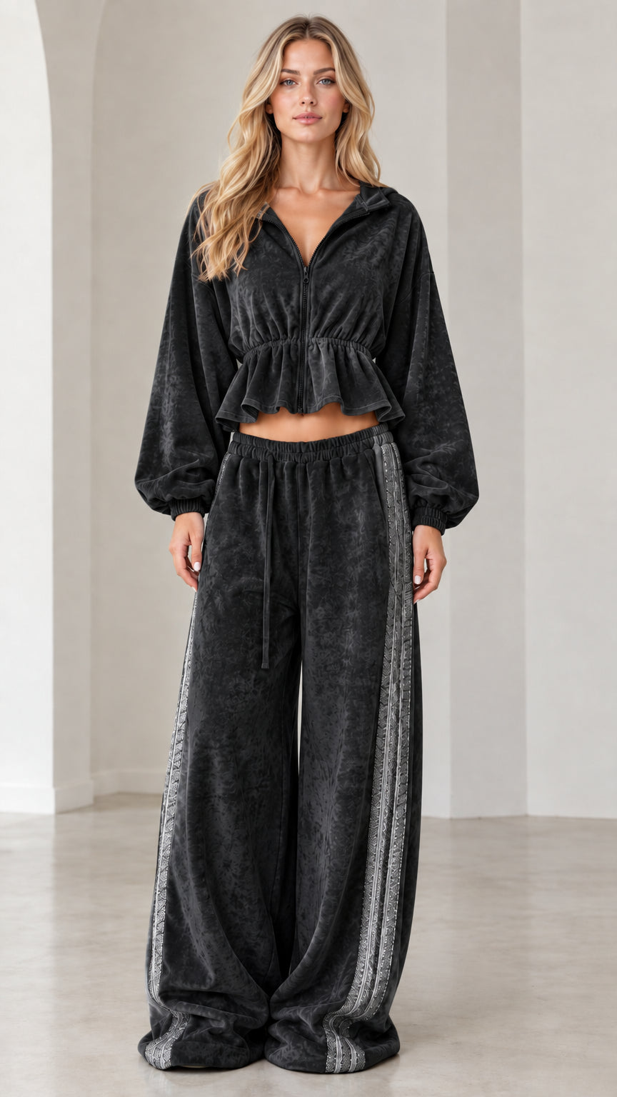 Full-length view of model wearing black velour cropped tracksuit set with side stripe wide-leg pants
