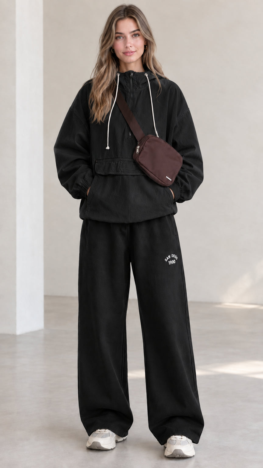 Full-length front view of model wearing black half-zip hooded anorak jacket