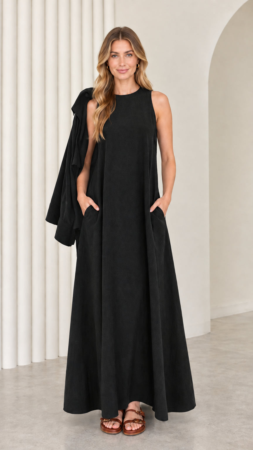 Front full-length view of model wearing the black sleeveless maxi dress with matching drape