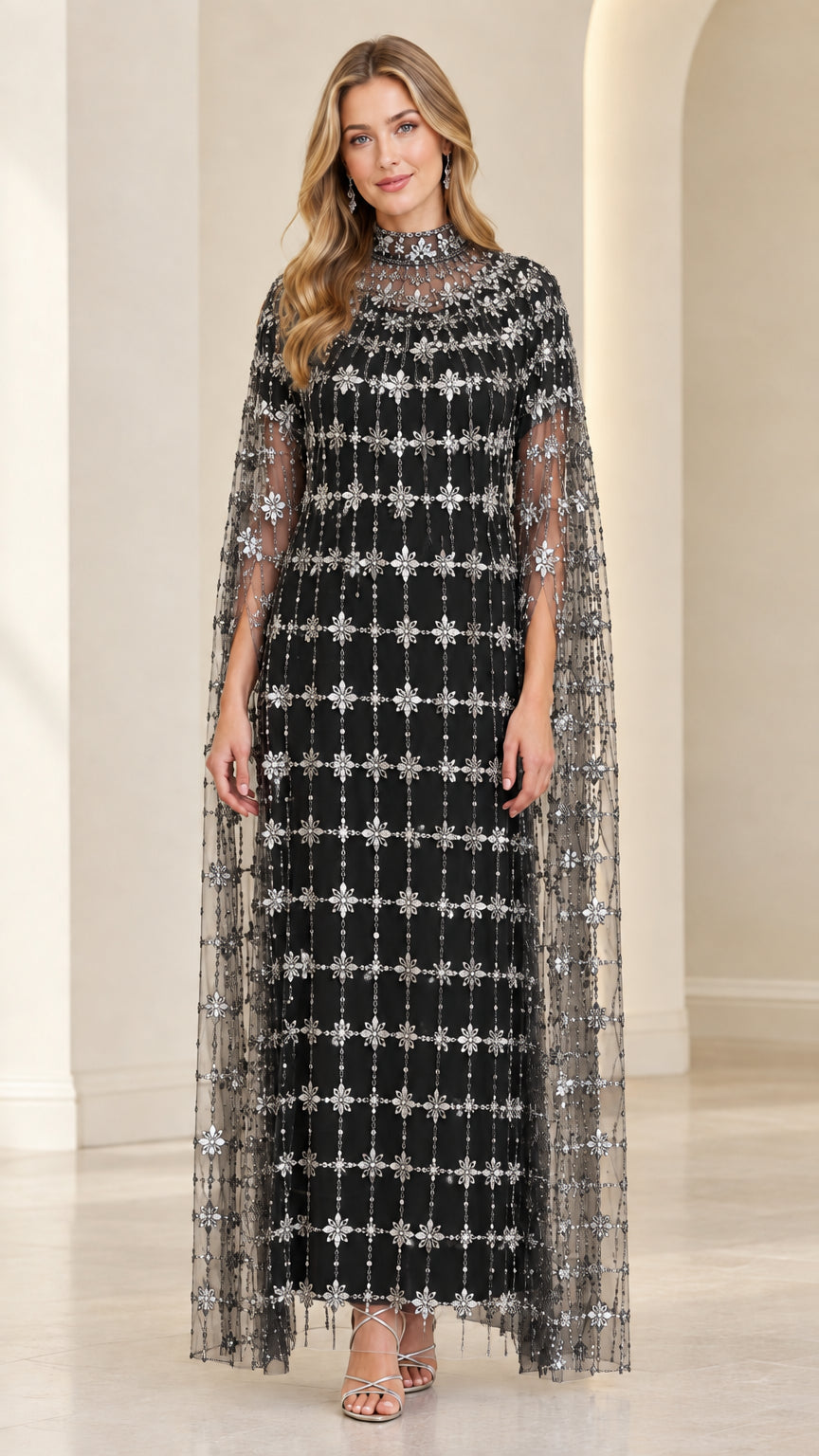 Front view of model in Black beaded formal gown with sweeping sheer cape