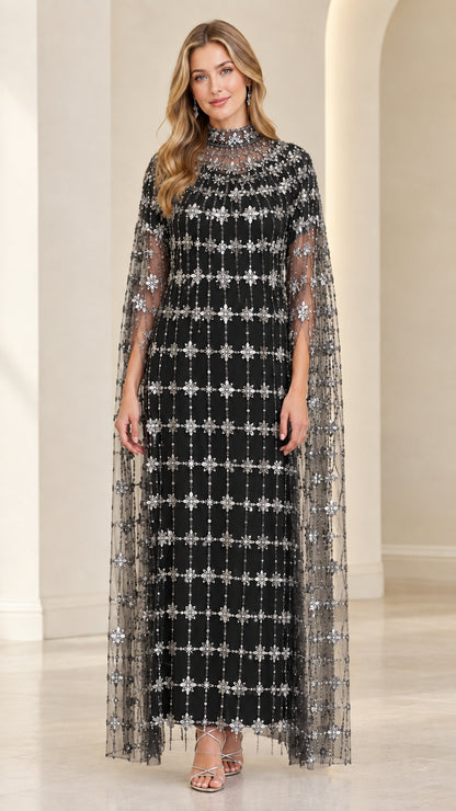 Front view of model in Black beaded formal gown with sweeping sheer cape