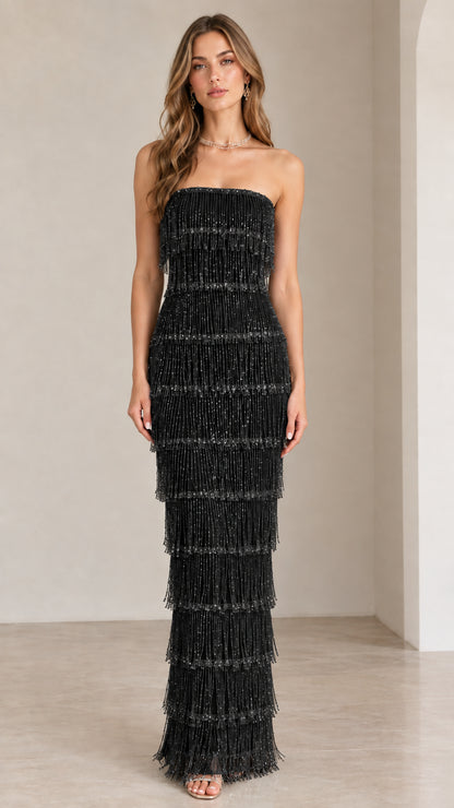 Front view of model wearing black strapless tiered fringe maxi gown