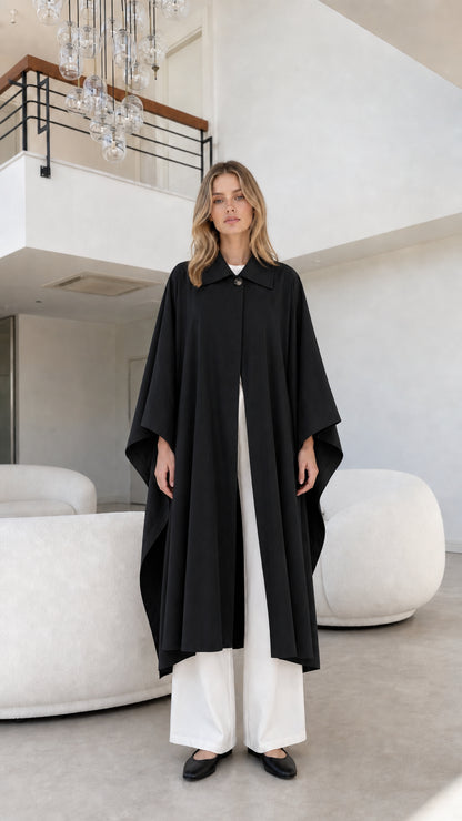 Full front view of model wearing black longline collared cape coat
