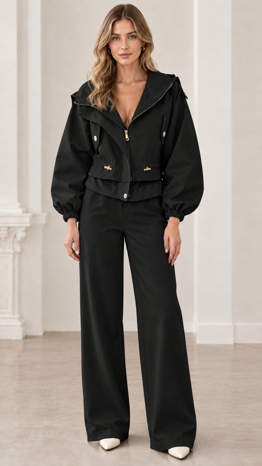 Front view of woman wearing black cropped hooded utility jacket with matching black pants