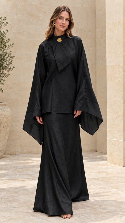 Model wearing black high-neck draped tunic and maxi skirt two-piece set