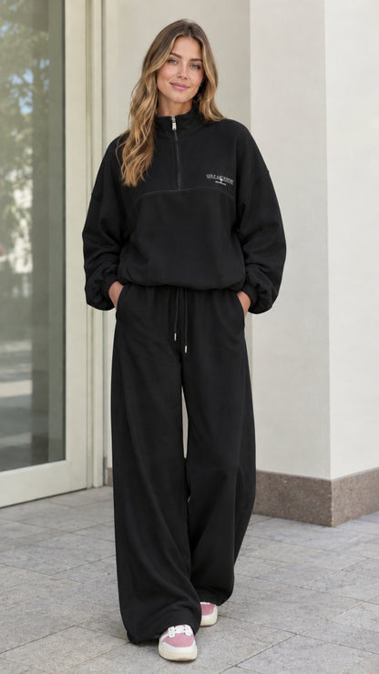 Woman wearing Black fleece quarter-zip pullover and wide-leg lounge pants set