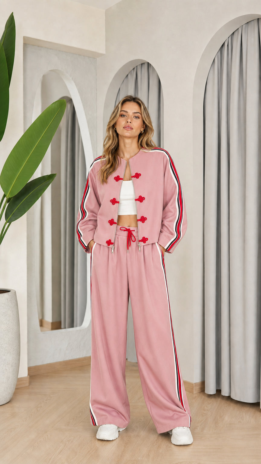 Model wearing dusty pink two-piece tracksuit set with red accents