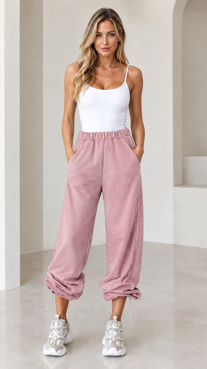 Model wearing dusty pink cinch-bottom joggers with side piping