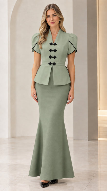 Front full view of woman wearing sage green peplum top and matching mermaid maxi skirt set