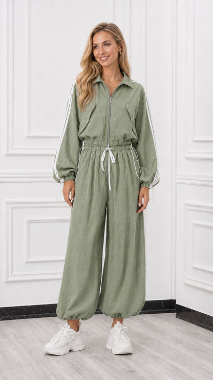 Front view of woman wearing a sage green sporty track jumpsuit with drawstring waist