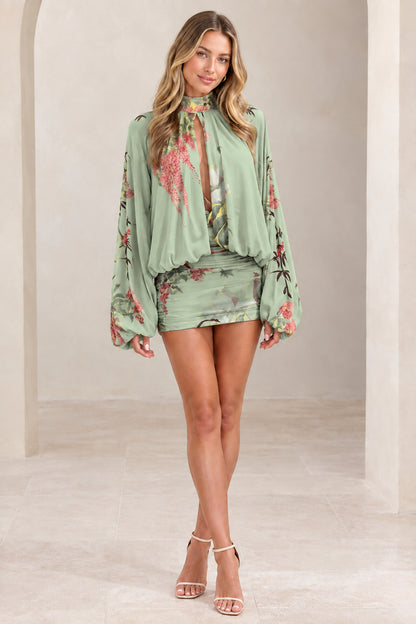 Woman wearing sage green floral balloon sleeve ruched mini dress