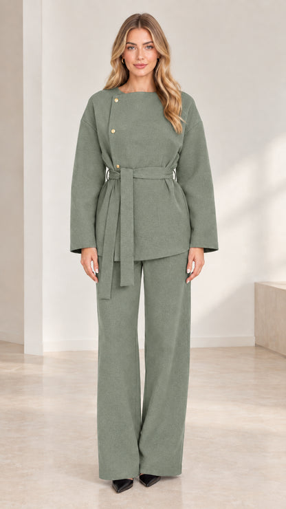 Full-length studio shot of model wearing sage green asymmetrical belted pant set
