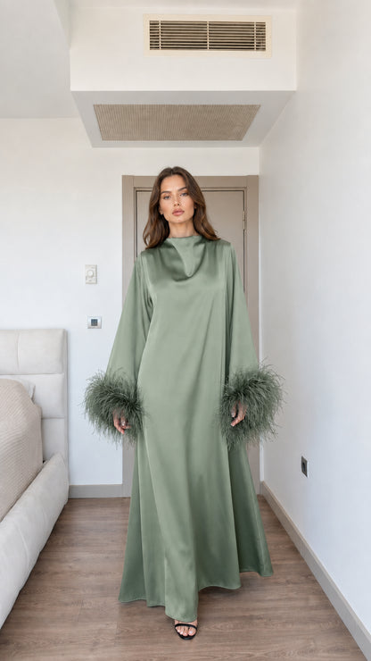 Model wearing sage green satin maxi dress with feather cuffs