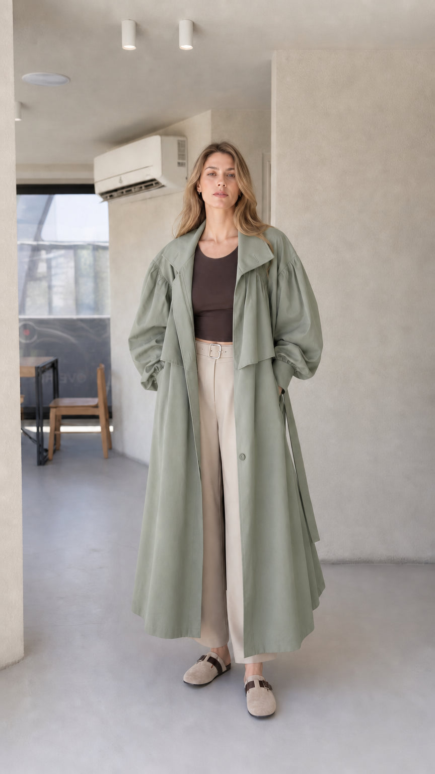 Model wearing sage green oversized maxi trench coat with removable waist belt