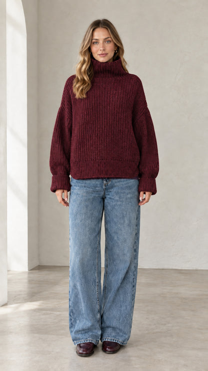 Model wearing burgundy wine red chunky ribbed knit turtleneck sweater