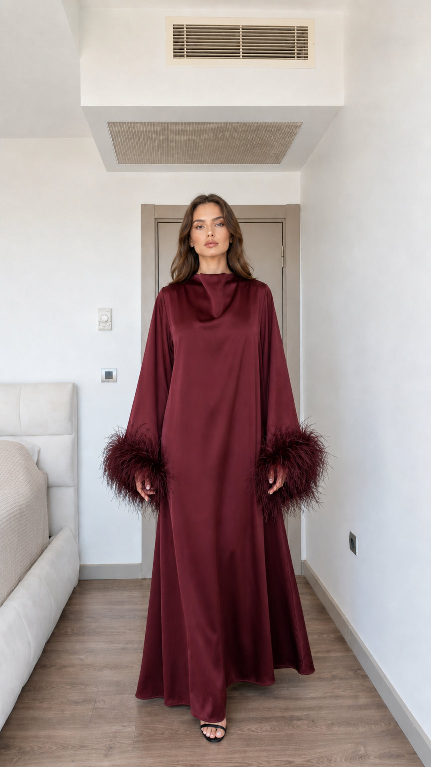 Model wearing rich burgundy wine red satin maxi dress with feather cuffs