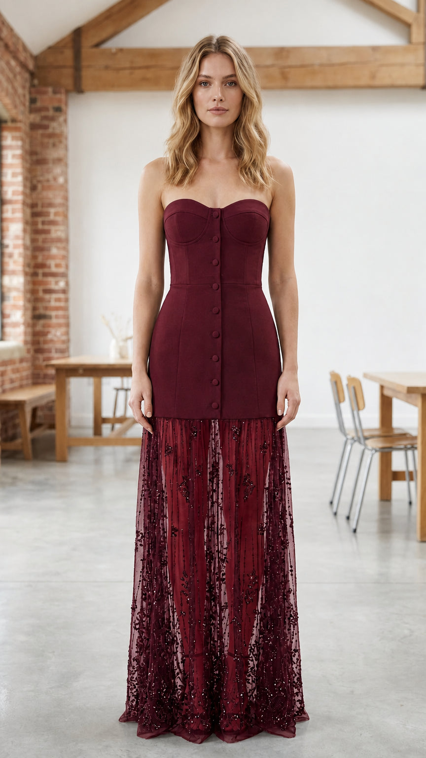 Full-length view of woman in burgundy red strapless corset evening dress with sheer sequin skirt