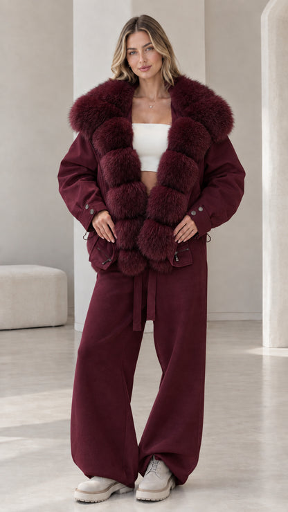 Model wearing deep burgundy jacket and pants set with matching wine plush collar