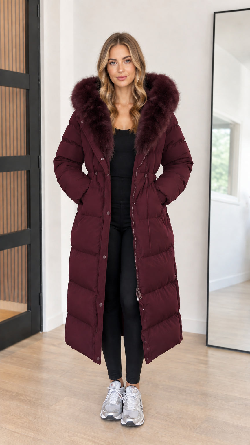 Full length view of women's deep burgundy maxi puffer coat with faux fur hood
