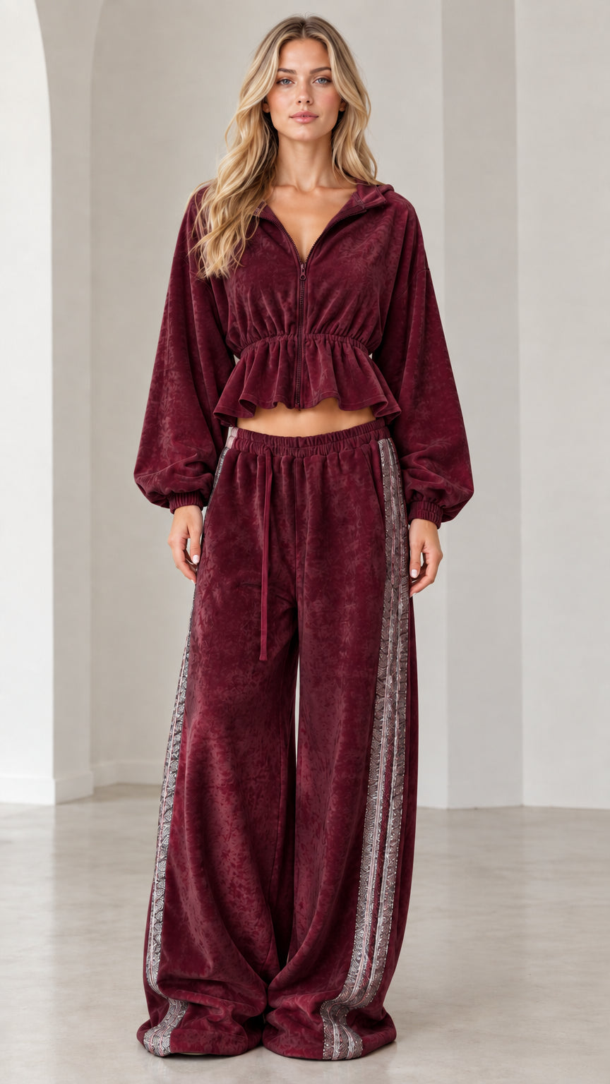 Full-length view of model wearing burgundy wine velour cropped tracksuit set with side stripe pants