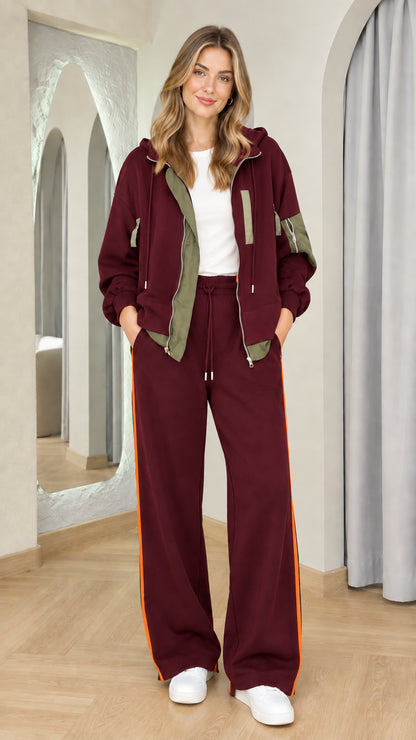 Woman wearing burgundy zip-up hoodie and matching wide-leg pants set with side stripe