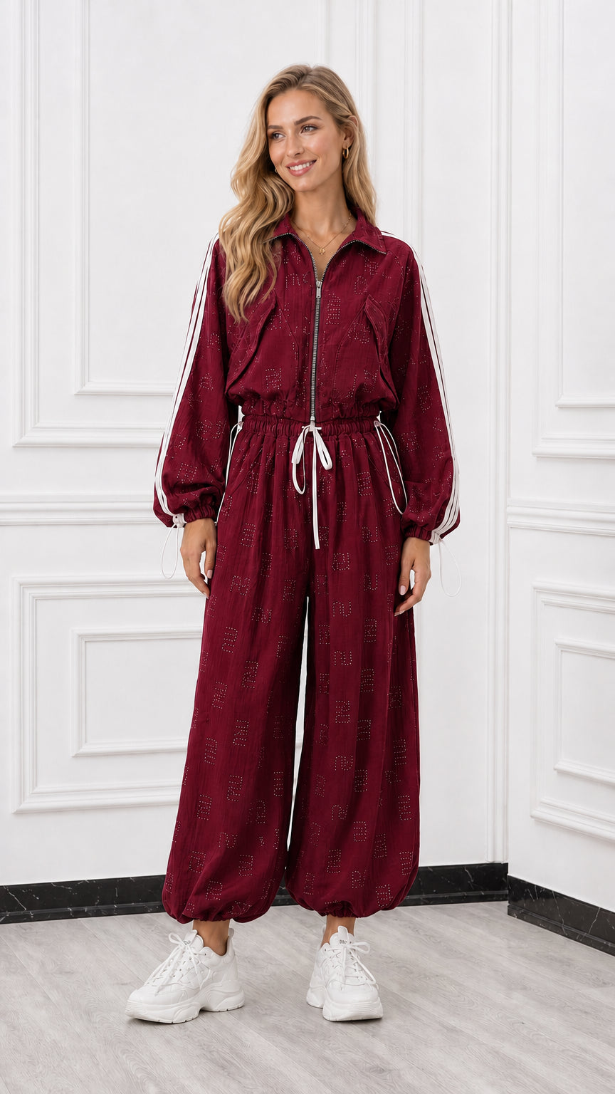 Front view of woman wearing a burgundy red zip-front track jumpsuit with white side stripes