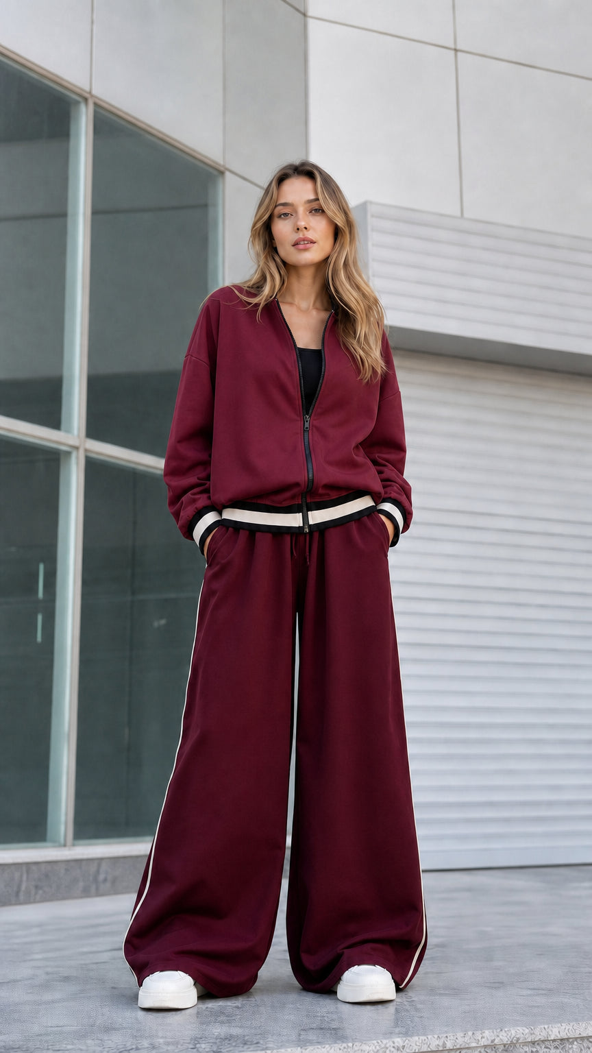 Model wearing monochrome burgundy 2-piece bomber jacket and wide leg tracksuit set