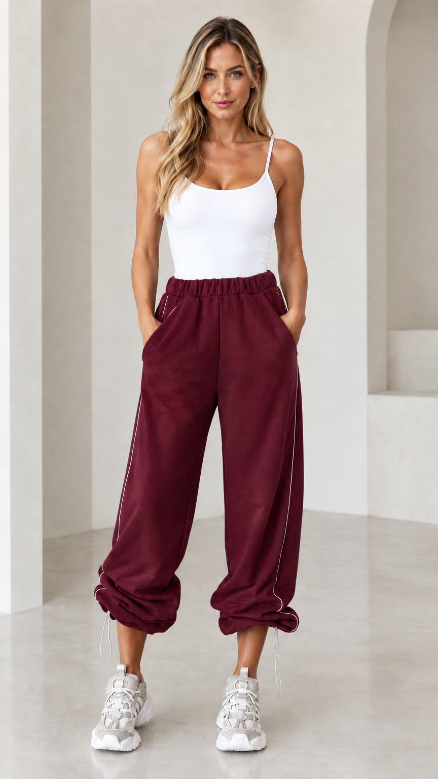 Model wearing burgundy wine red relaxed joggers with side piping