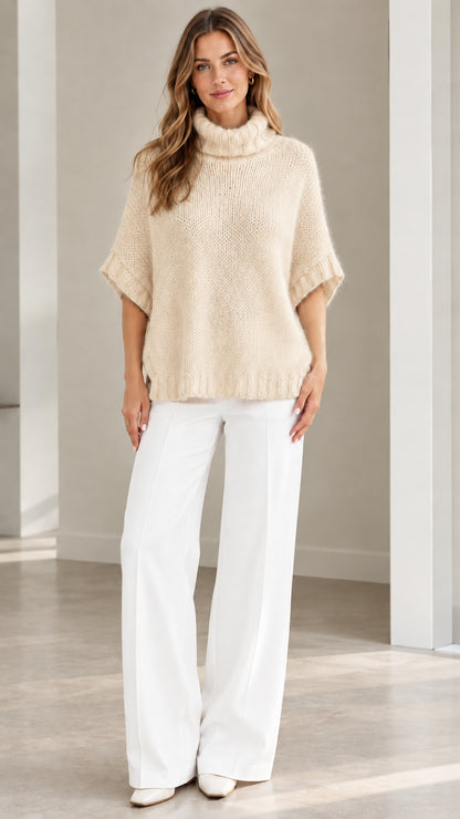 Model wearing Cream beige fuzzy knit turtleneck poncho sweater